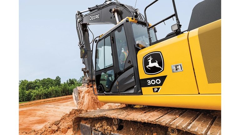 A close-up of the side of a 300P-Tier Excavator as it dumps dirt into a pit at a worksite.