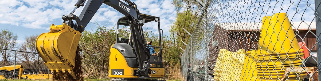 Closeup of a John Deere 60G Compact Excavator's bucket moving dirt on a job site.
