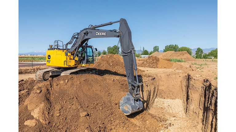 A 345P-Tier Excavator scooping dirt out of a pit at a worksite.