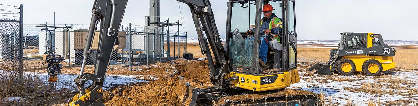 35G Mini Excavator digging dirt between a fence and a deck in a residential landscaping project