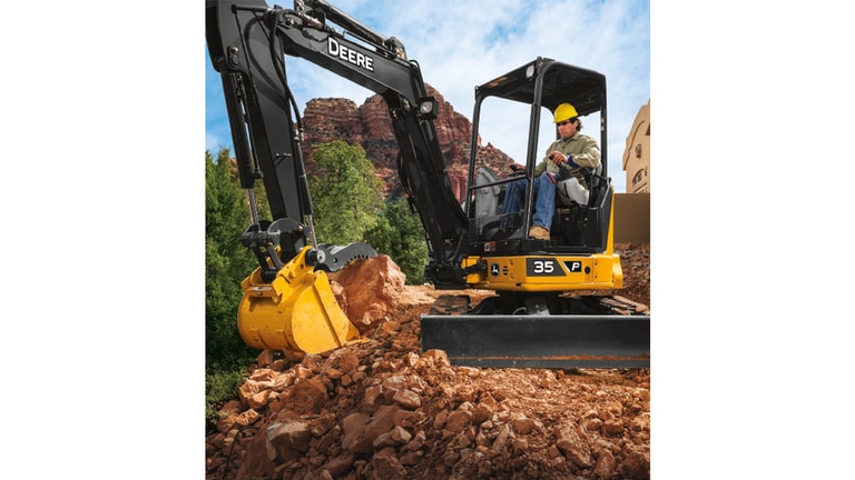 Un opérateur qui utilise une excavatrice 35P-Tier pour déplacer de gros morceaux de roche avec des formations de roche rouge en arrière-plan.