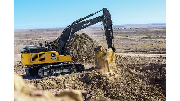 A 470-P-Tier Excavator scooping up dirt on top of a hill at a worksite.