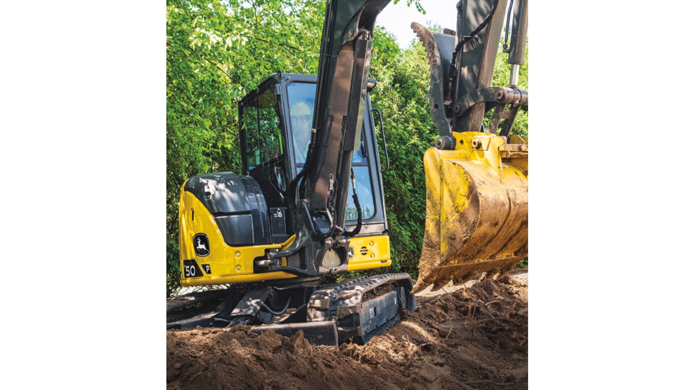 A 50P-Tier Excavator moving dirt with trees in the background.