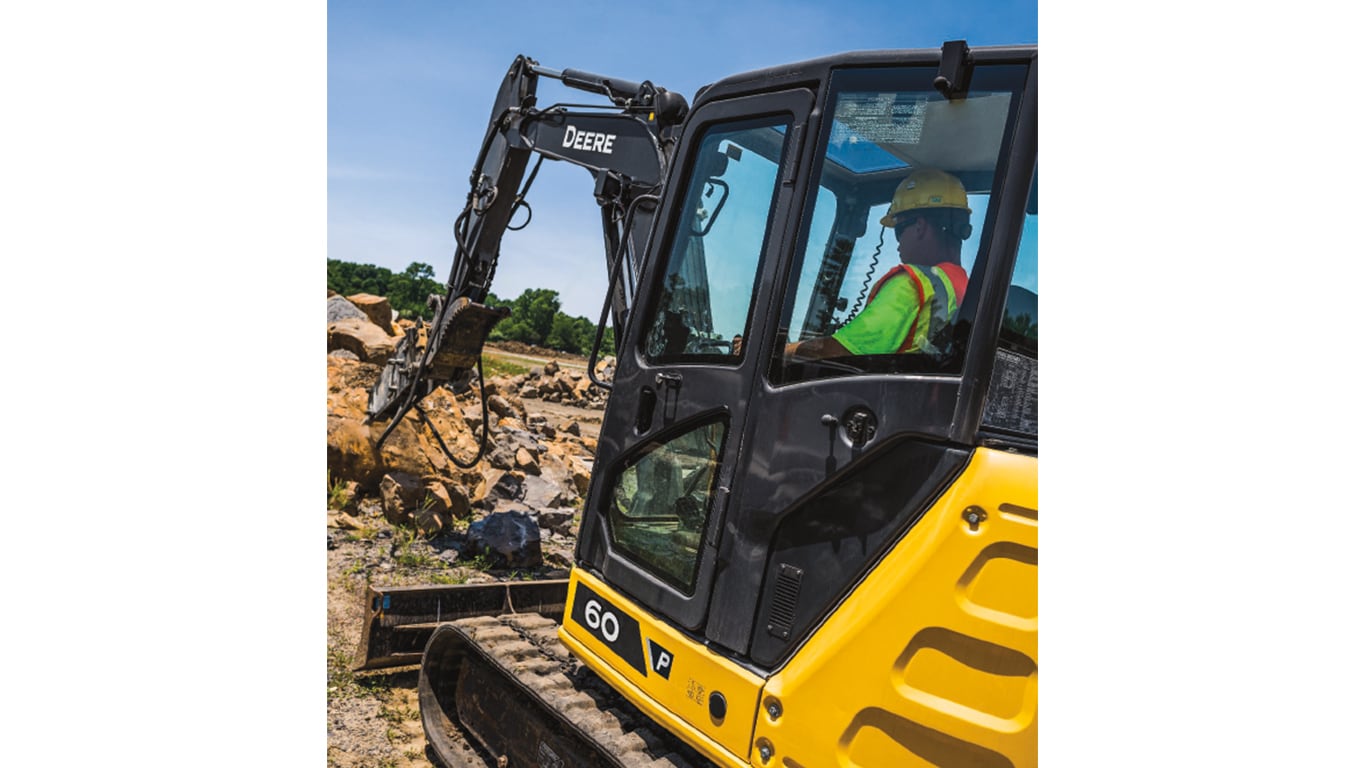 Un opérateur qui utilise une excavatrice 60P-Tier pour ramasser des roches sur un chantier.