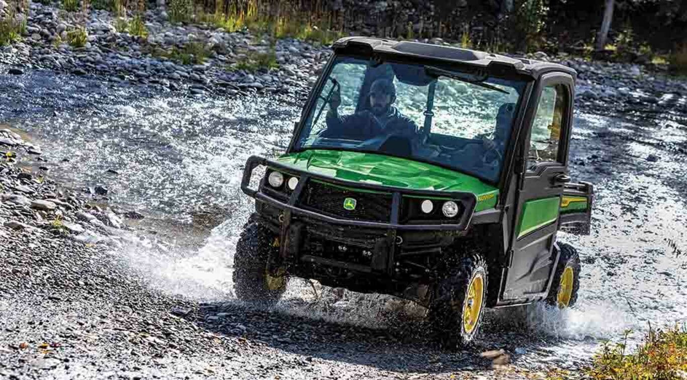 a XUV835M Gator driving through a shallow river bed.