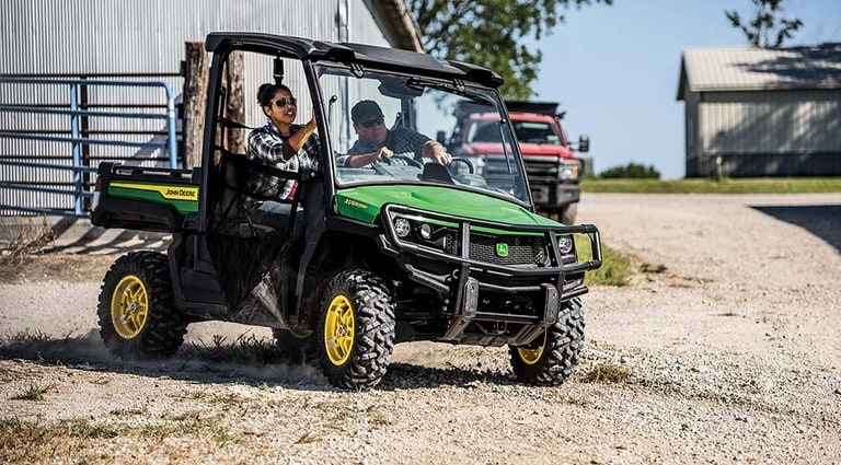 Deux personnes circulant à bord d’un Gator XUV835M sur du gravier.