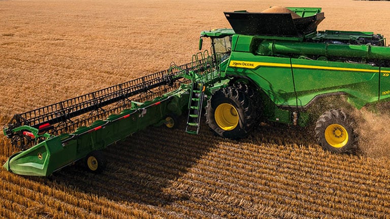 Photo d’une moissonneuse-batteuse X9 John Deere récoltant du blé avec une tête de coupe de tablier à toile.