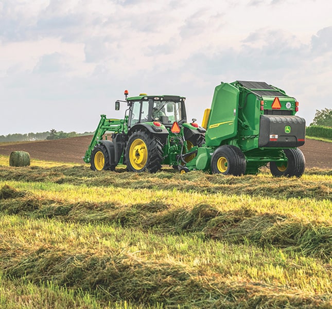 Tracteur tirant une presse le long d’un andain.