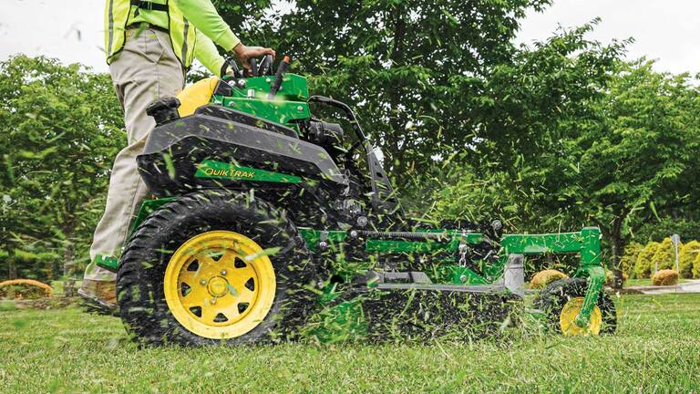 Vue lat&eacute;rale des brins d&rsquo;herbe coup&eacute;s qui sont d&eacute;vers&eacute;s du corps de tondeuse &agrave; conducteur debout QuikTrak&trade; Q850R.