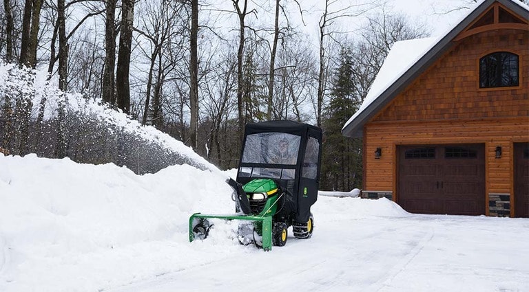 Une personne déneigeant son allée avec son tracteur X350 doté d’une souffleuse