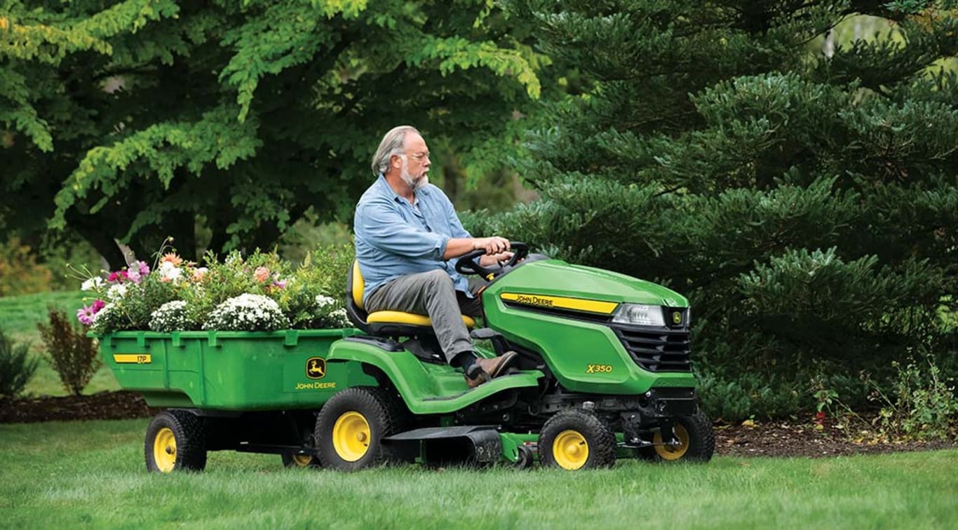 Une personne utilisant la remorque de son tracteur X350 pour transporter des fleurs.