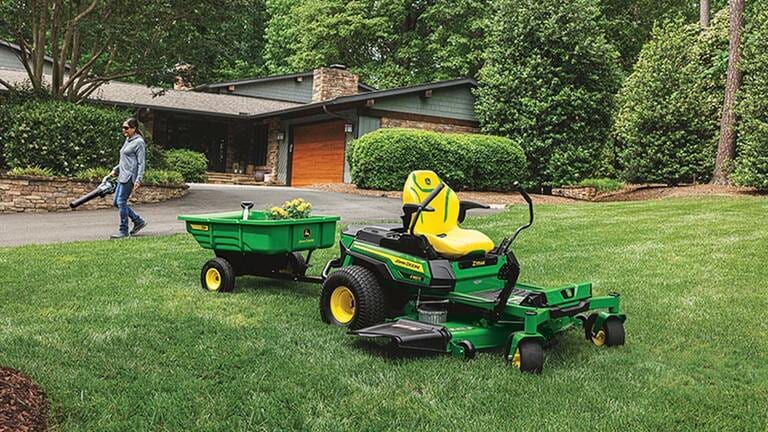 Personne qui souffle de l’herbe avec une tondeuse Z380R et une remorque 7P en avant-plan