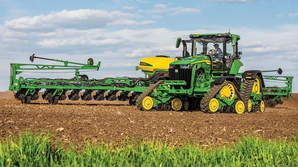 The front of a John Deere tractor pulling a planter.