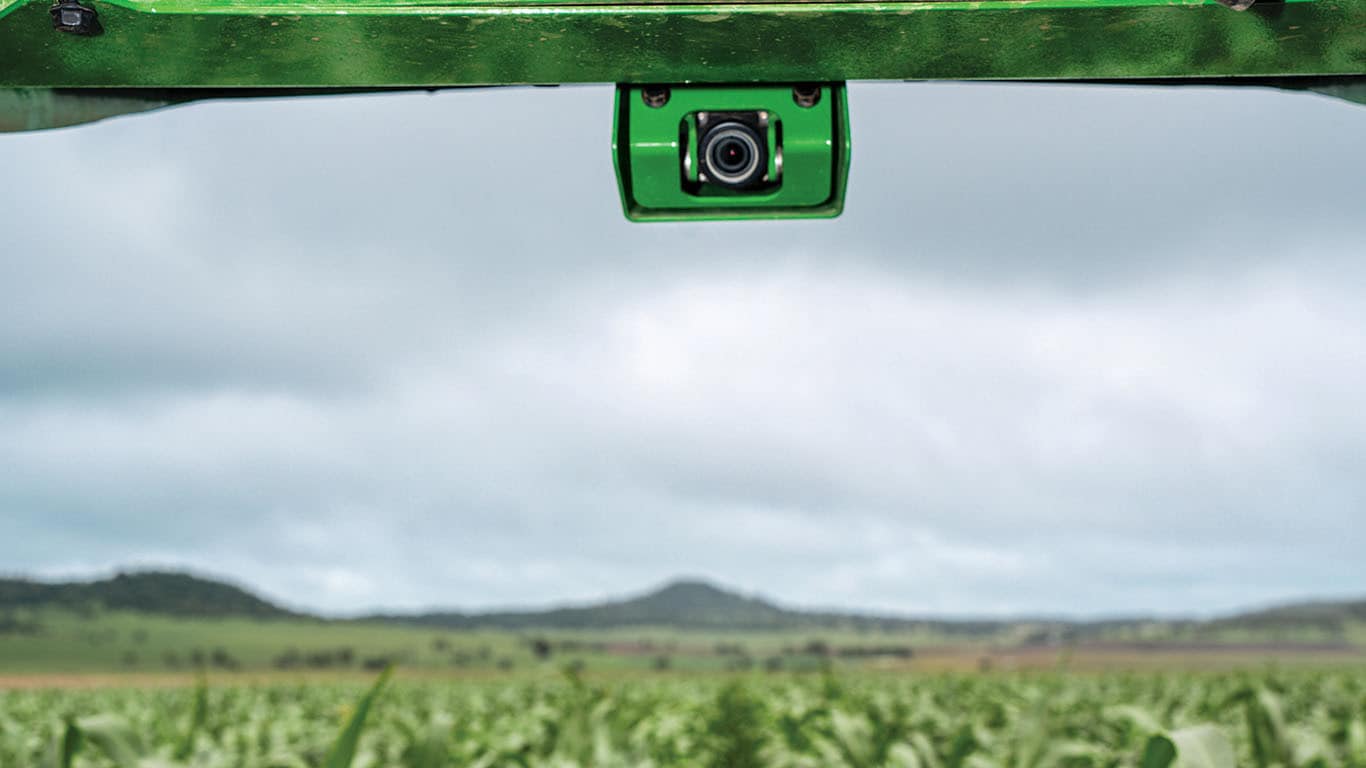 Closeup of a green camera pointed down at a crop field