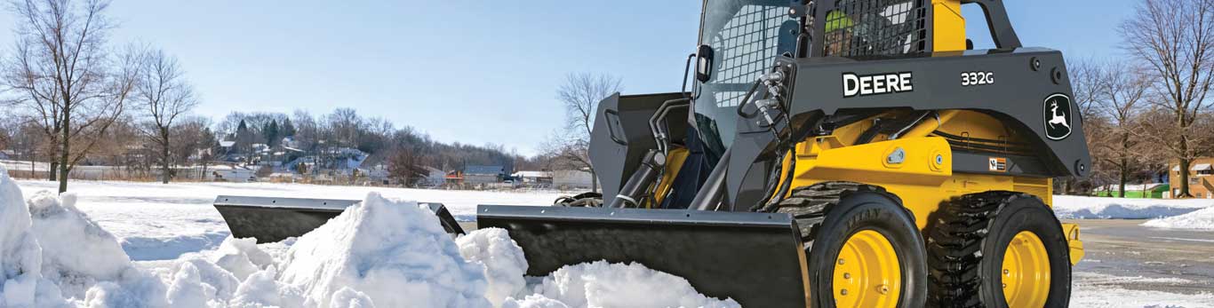 332G Large Skid Steer pushes snow in a parking lot with a V blade attachment