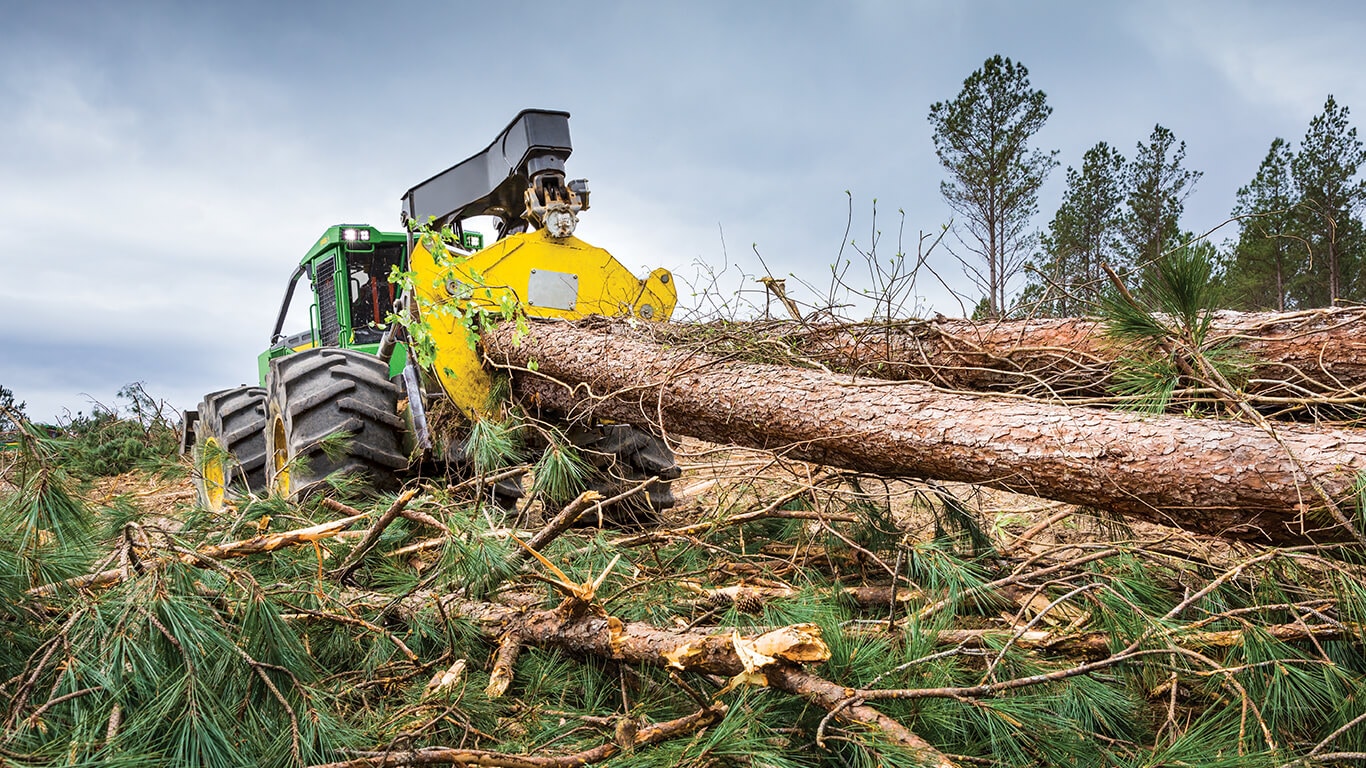 John Deere skidder moving three large logs on landing site