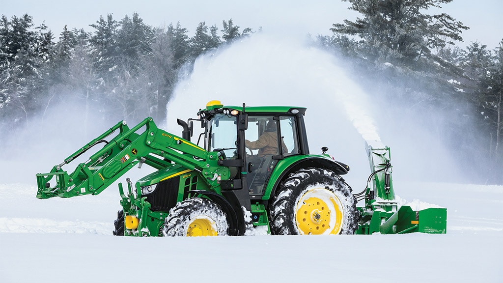 Tracteur 6M avec chargeur et chasse-neige soufflant la neige en hiver