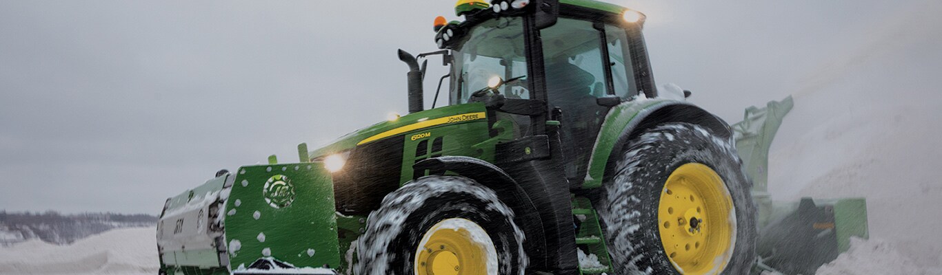 Tracteur de série 6M avec chasse-neige soufflant la neige en hiver