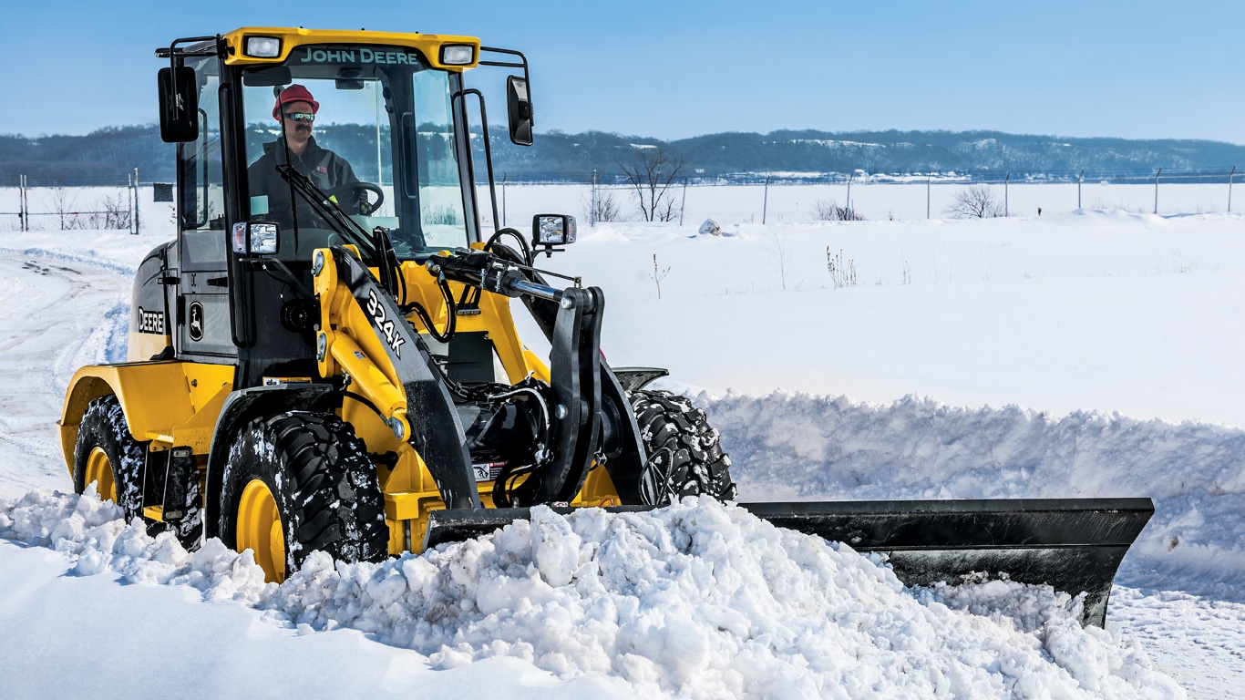 A 324K wheel loader with BL10B snow blade attachment plowing snow.