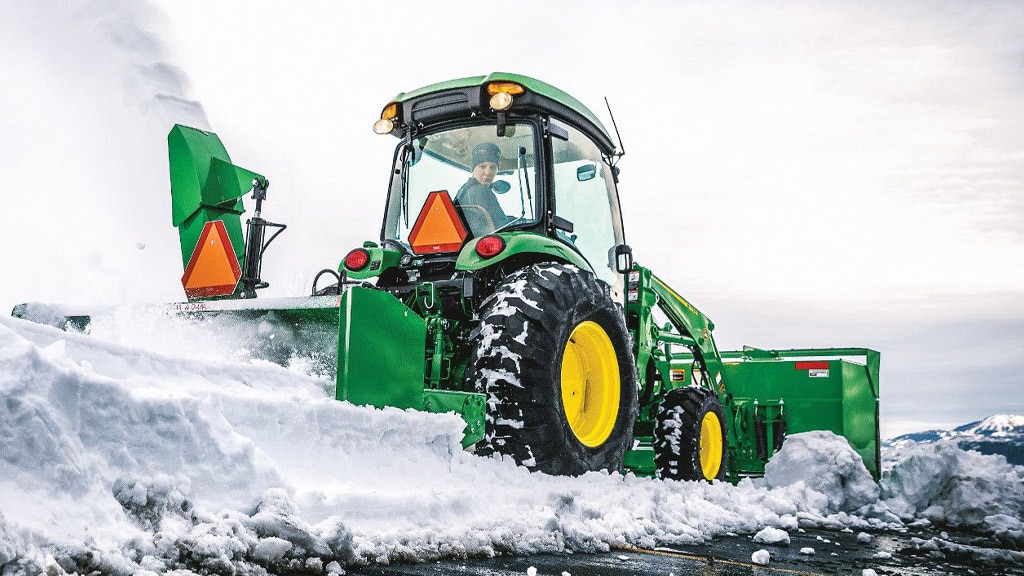 Person clearing parking lot using a 4066r compact tractor and SB1184 snow blower