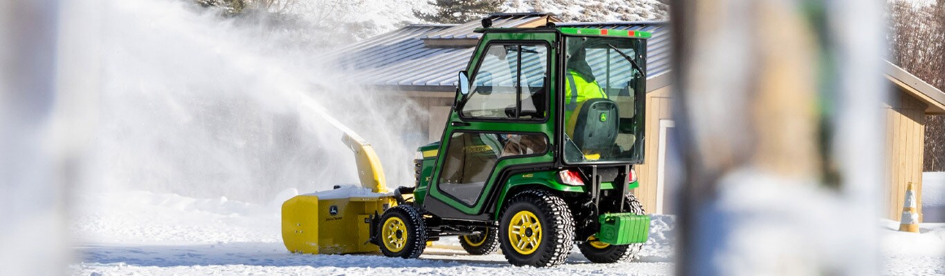 Man riding an X700 lawn tractor blowing snow in yard.