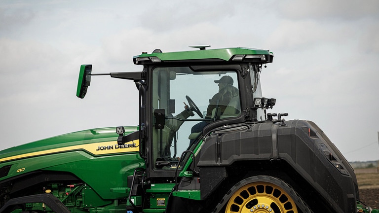 Personne dans un tracteur vert équipé d'un boîtier JDLink Boost fixé sur le toit.