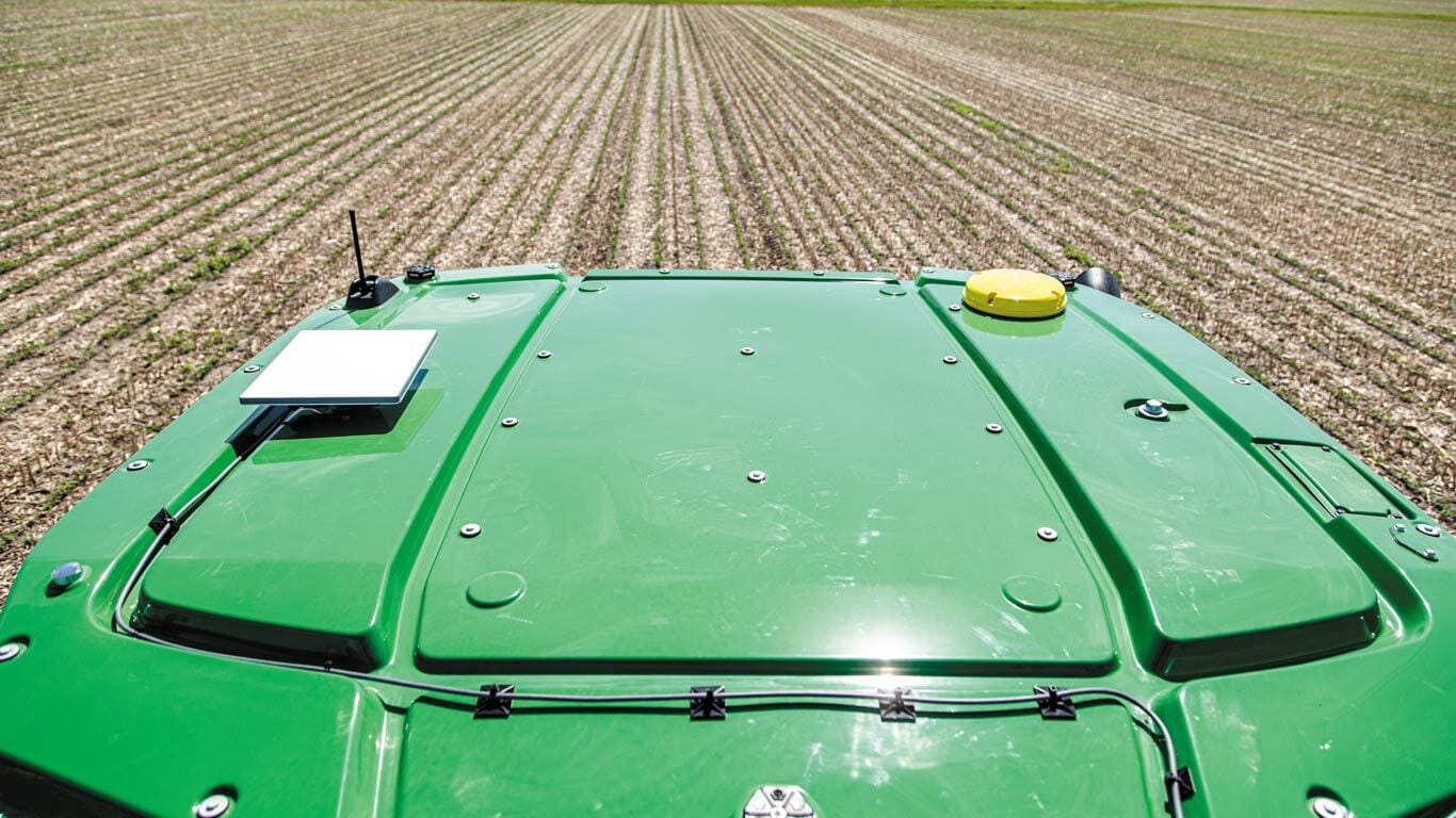 Gros plan sur un JDLink Boost fixé sur le toit d'un tracteur dans un champ.