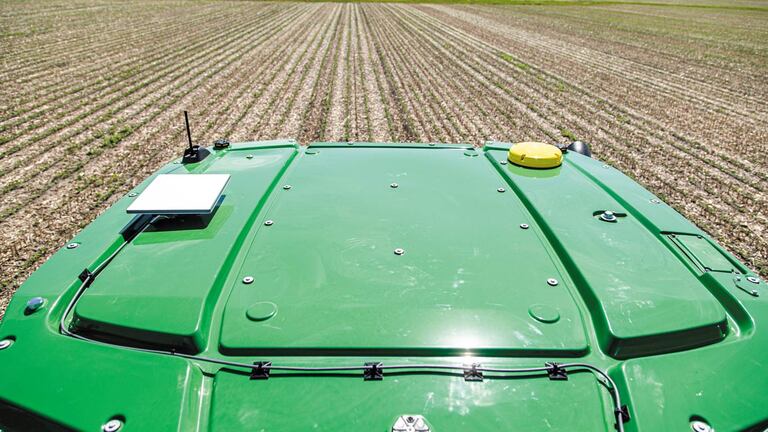 Gros plan sur un JDLink Boost fixé sur le toit d'un tracteur dans un champ.