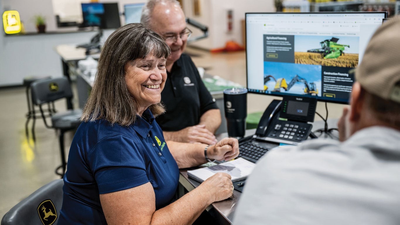 Des personnes travaillant ensemble à un bureau tout en consultant des renseignements sur un écran d’ordinateur.
