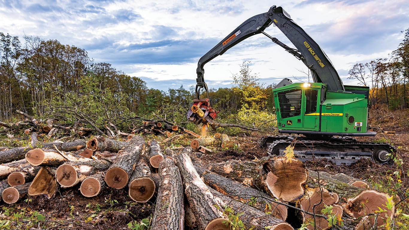 Une abatteuse-façonneuse chenillée de John Deere déposant un rondin dans une pile de rondins.