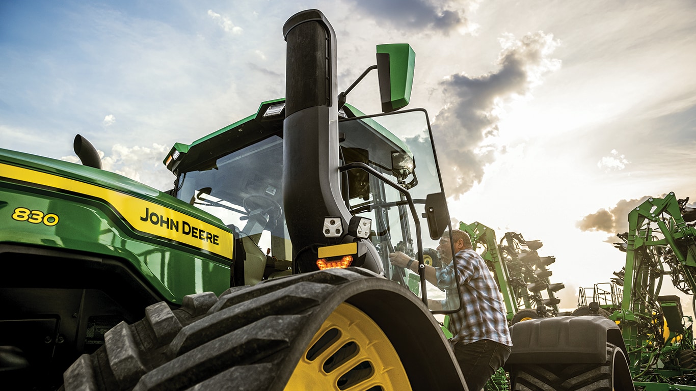 Homme entrant dans la cabine d'un tracteur 9RX 830