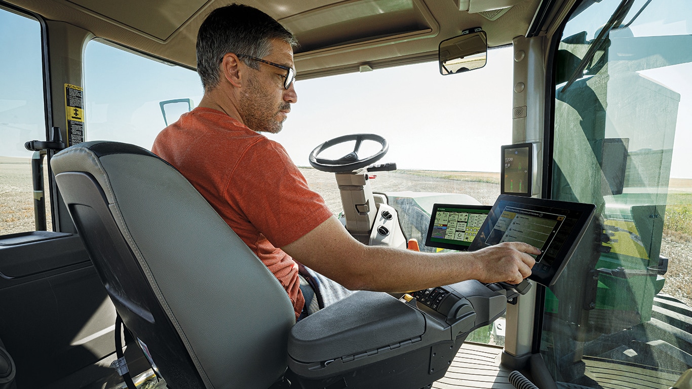 Conducteur interagissant avec l'afficheur dans la cabine du tracteur 9RX