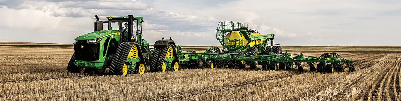 Tracteur 9RX 830 tirant un semoir pneumatique et une remorque pneumatique dans un champ​