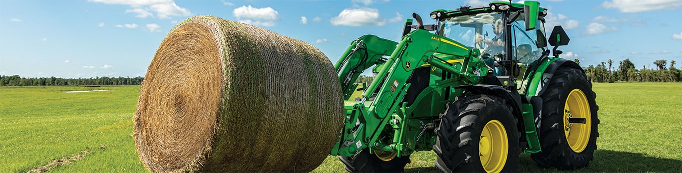 Tracteur 6R de John Deere déplaçant des balles rondes