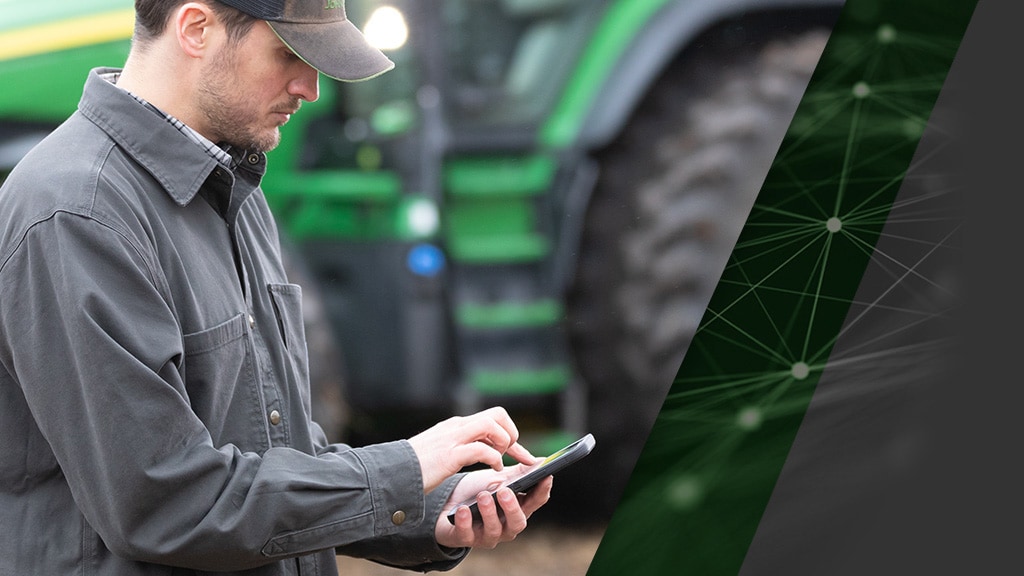 Photo d’un fermier utilisant son téléphone intelligent pour démarrer un tracteur autonome 8R John Deere