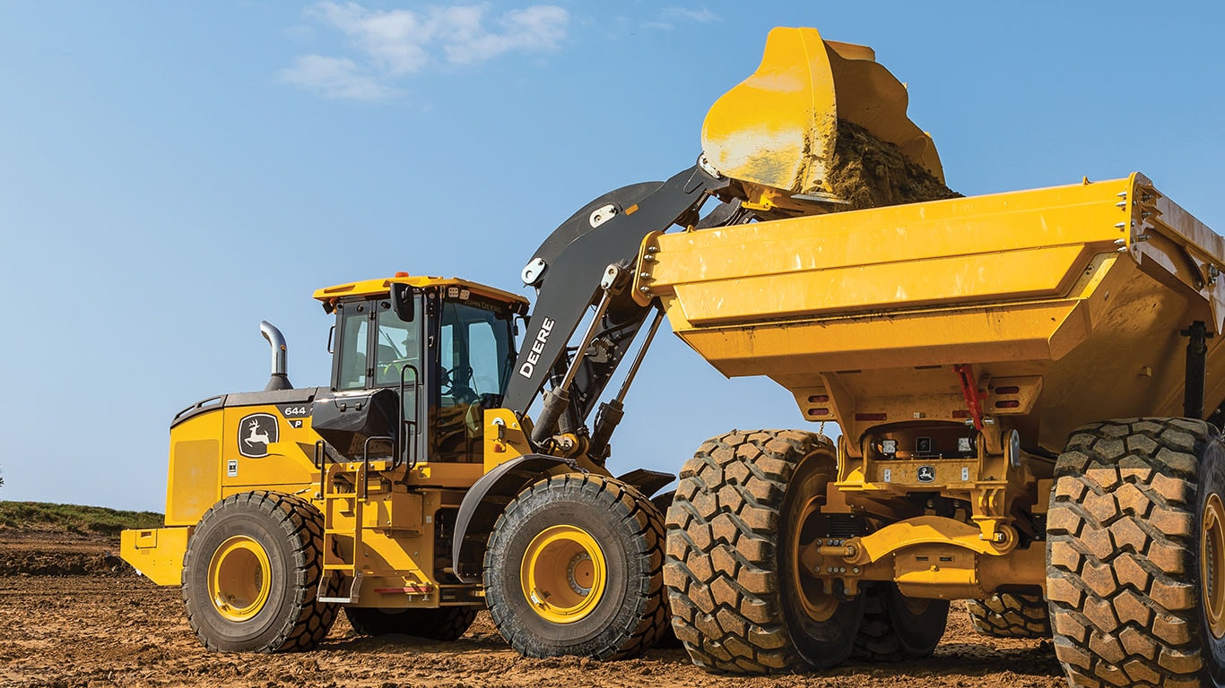 644 P-Tier four-wheel-drive loader dumping a bucket of dirt into the back of a dump truck on a site development jobsite.