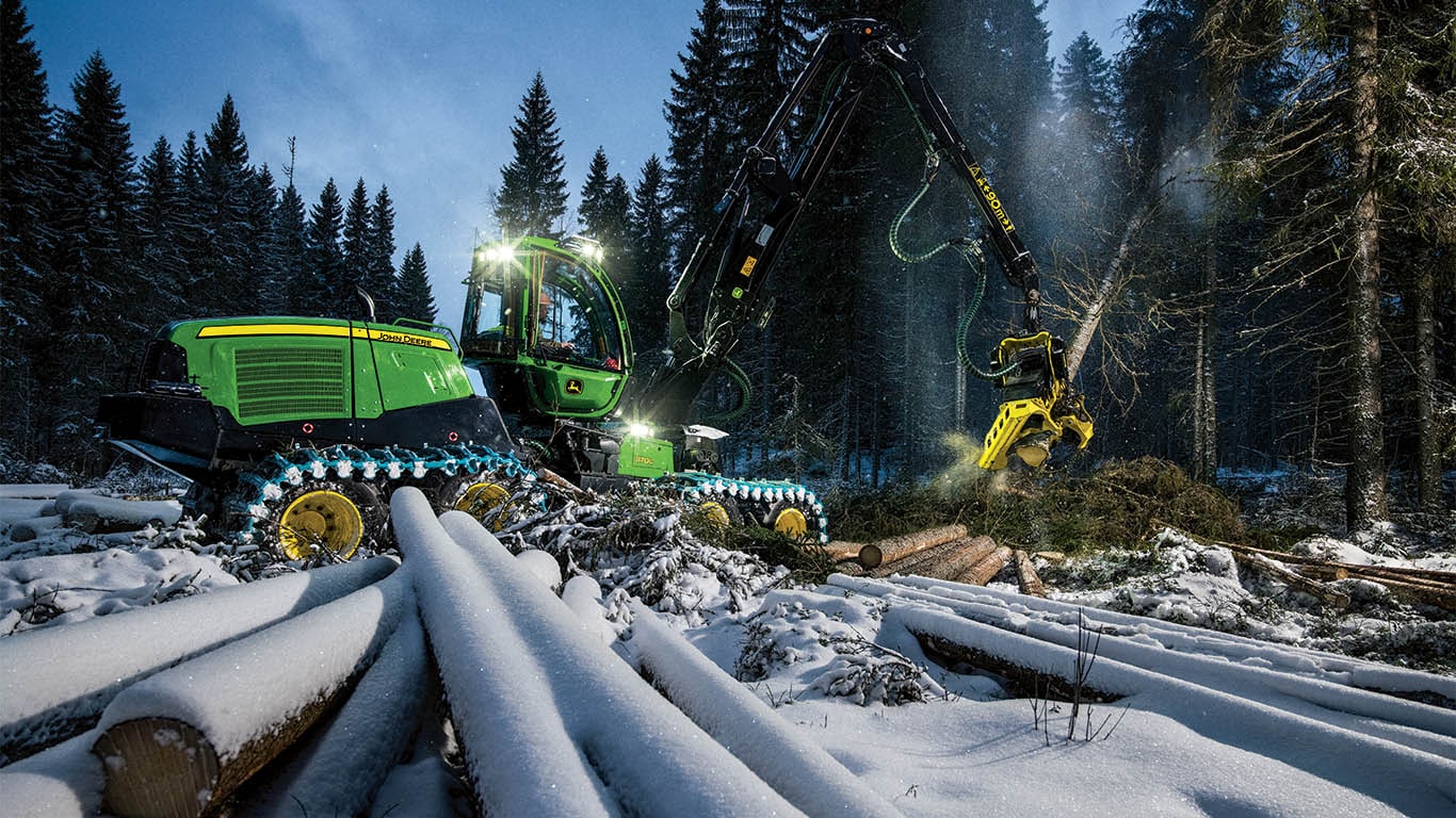 Une abatteuse-façonneuse à roues John Deere se préparant à abattre un arbre dans une forêt.