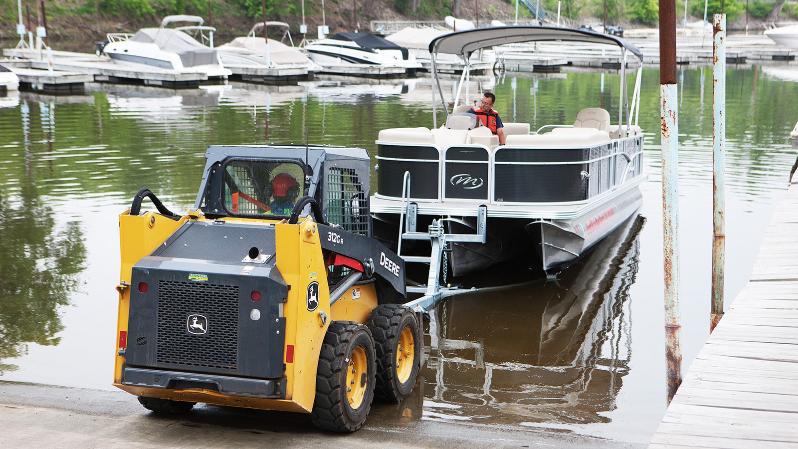 312GR Skid Steer pulls a pontoon boat out of the water