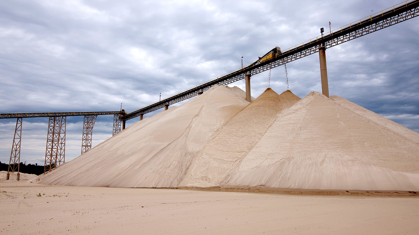 A conveyer drops loads onto already massive piles of sand