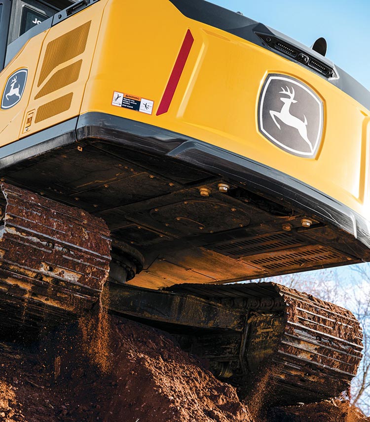 The back of a John Deere Excavator sits on a bench of dirt.