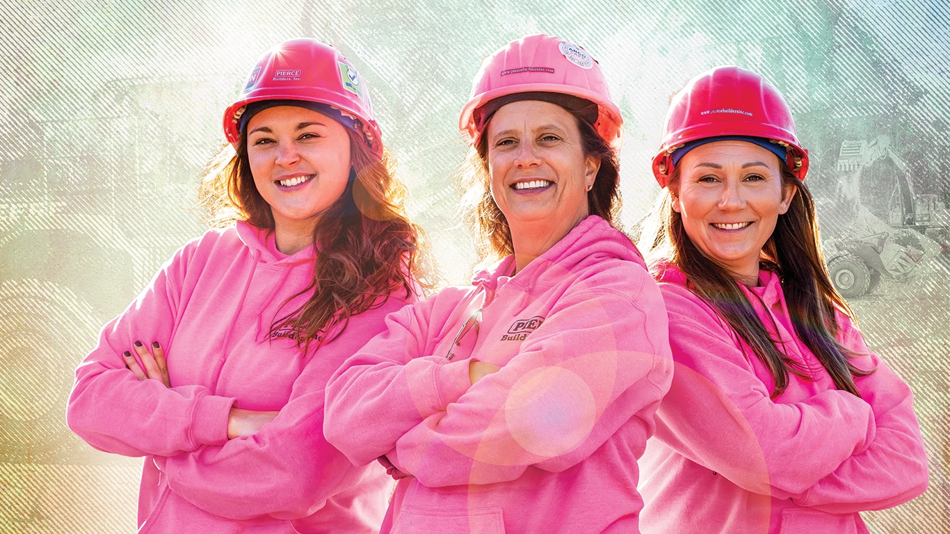 Missy Madden, Alescia Pierce et Erin McFague se tiennent debout et portent des chandails en molleton et des casques roses.