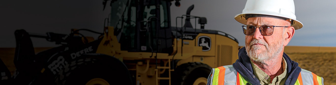 Chuck Dursma, civil superintendent at Blattner Energy, stands beside the John Deere 872GP Motor Grader on a jobsite in Montana.