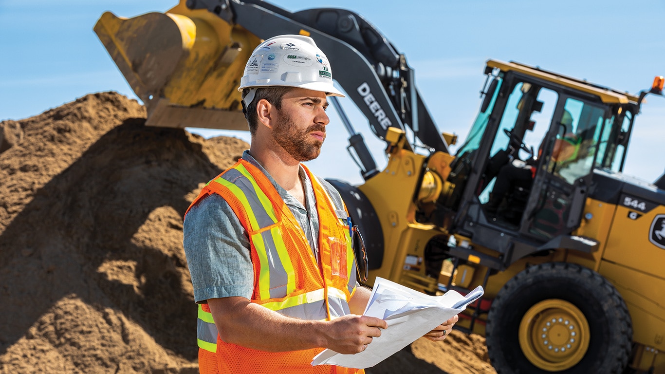 Jason Bast, general manager of NIS Contractors, assesses a jobsite in Regina, Saskatchewan as a 544 G Tier Wheel Loader works in the background.