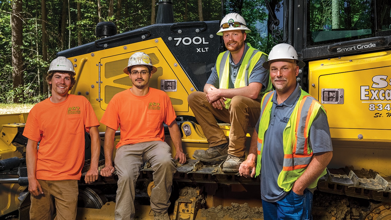 Dylan Nussbaum, Colt Nussbaum, Cody Nussbaum et Jesse Nussbaum posent près d’un bouteur chenillé 700L XLT SmartGrade de John Deere.