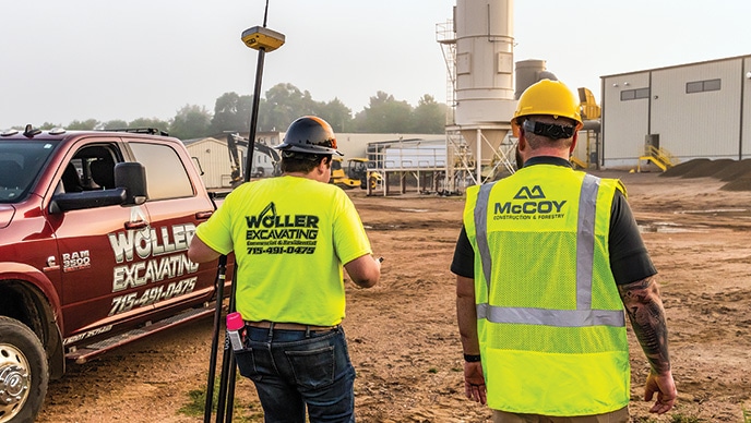 Brett Woller, propriétaire de Woller Excavating, transporte un récepteur du système de positionnement Topcon fixé à un trépied et marche à côté de Taylor Long, un représentant technologique du soutien technique pour McCoy Construction & Forestry.