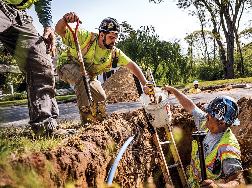 Ilidio hands a bucket to co-worker John as the two men work together on a project in Cape Cod.
