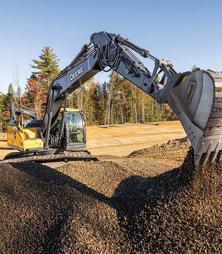 A John Deere Excavator extends its boom to scoop a bucket of rock