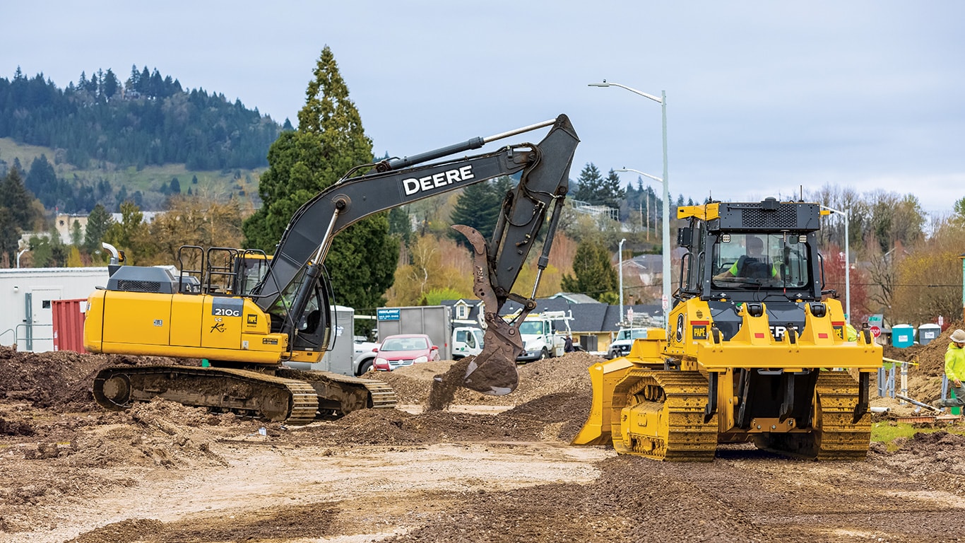 Une excavatrice 210G LC de John Deere au travail à côté d’un bouteur 750L sur un chantier de Kipco Construction en Oregon.