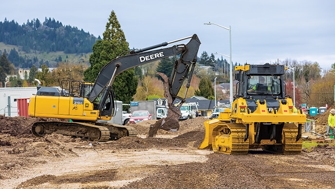 Une excavatrice 210G LC de John Deere travaillant avec un bouteur 750L sur un chantier de Kipco Construction en Oregon.