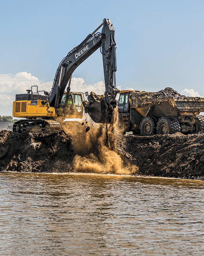 A John Deere 470G LC Excavator and a 410E‑II Articulated Dump Truck work together restoring a lagoon in southern California.